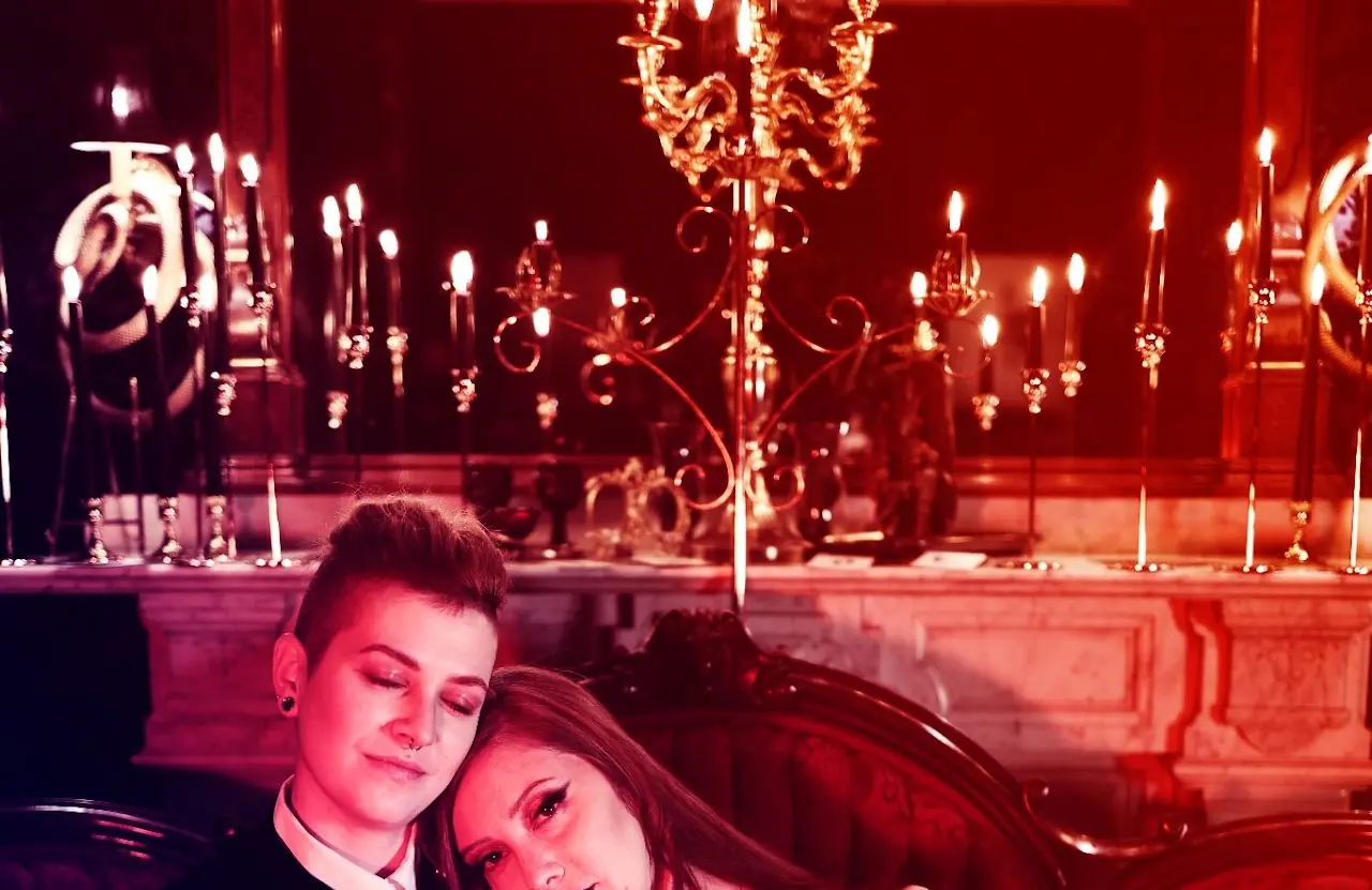 A couple resting together beneath red chandelier light