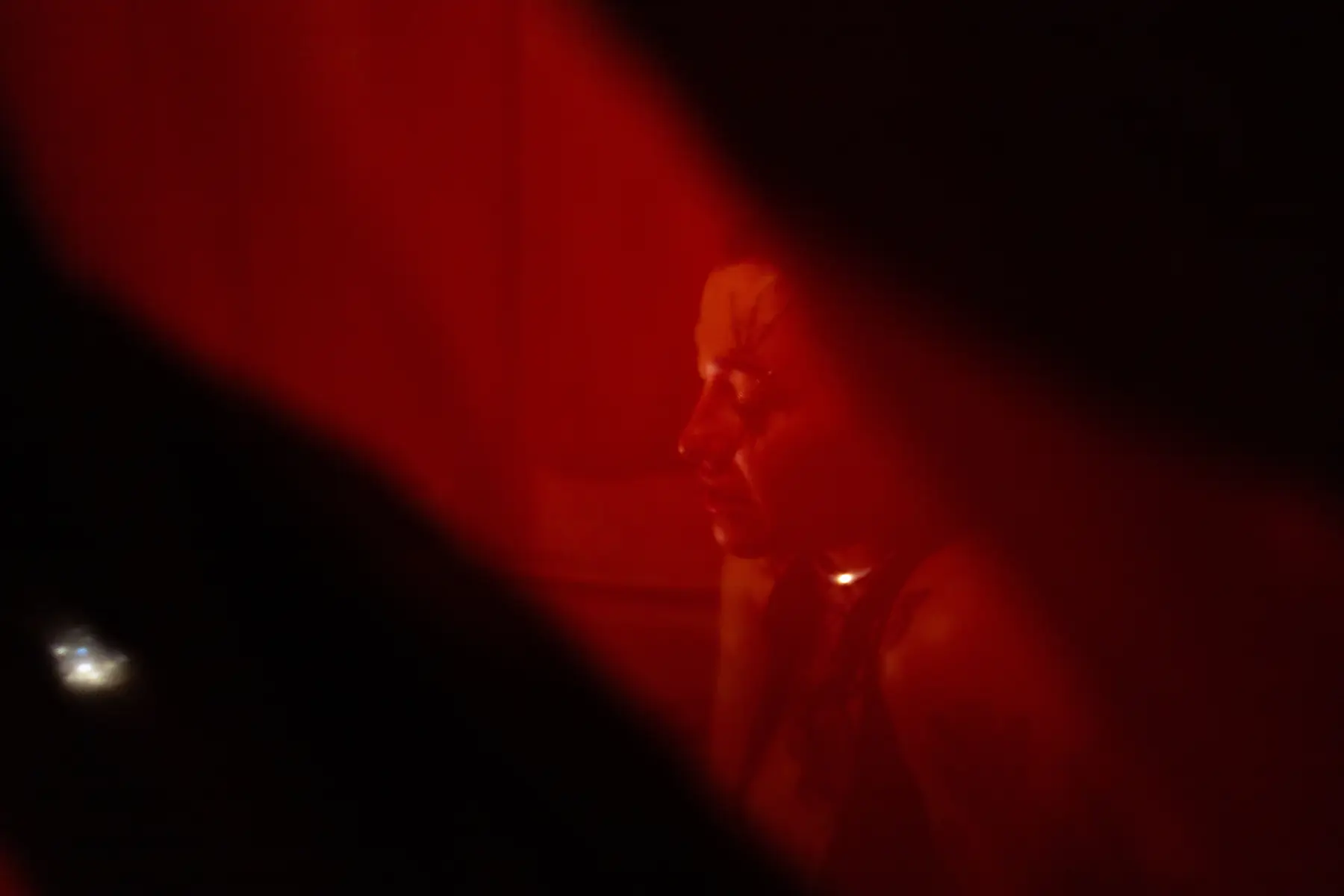 A shadowed figure glowing behind a translucent red veil