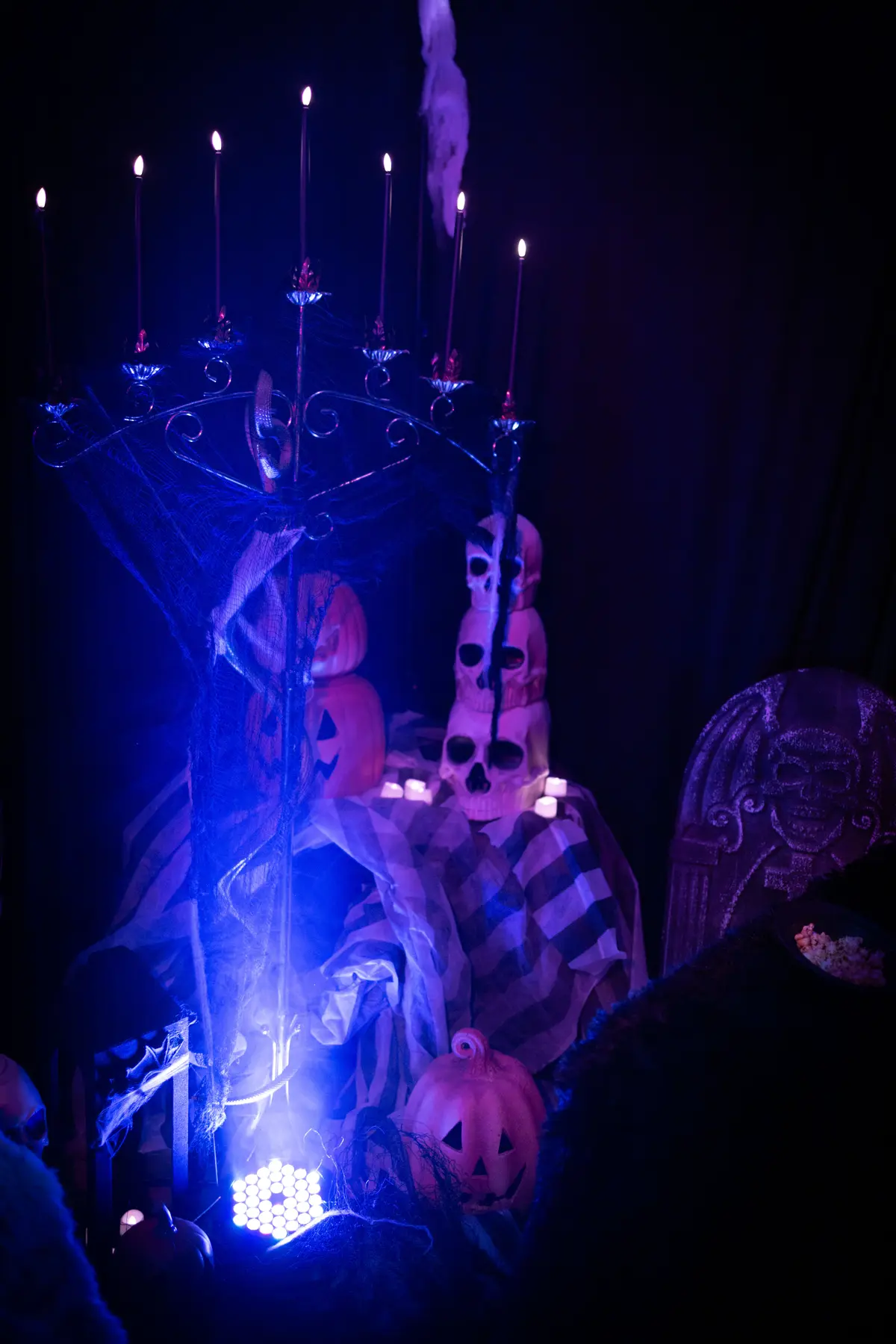 Blue-lit candelabra surrounded by pumpkins and sculptural figures
