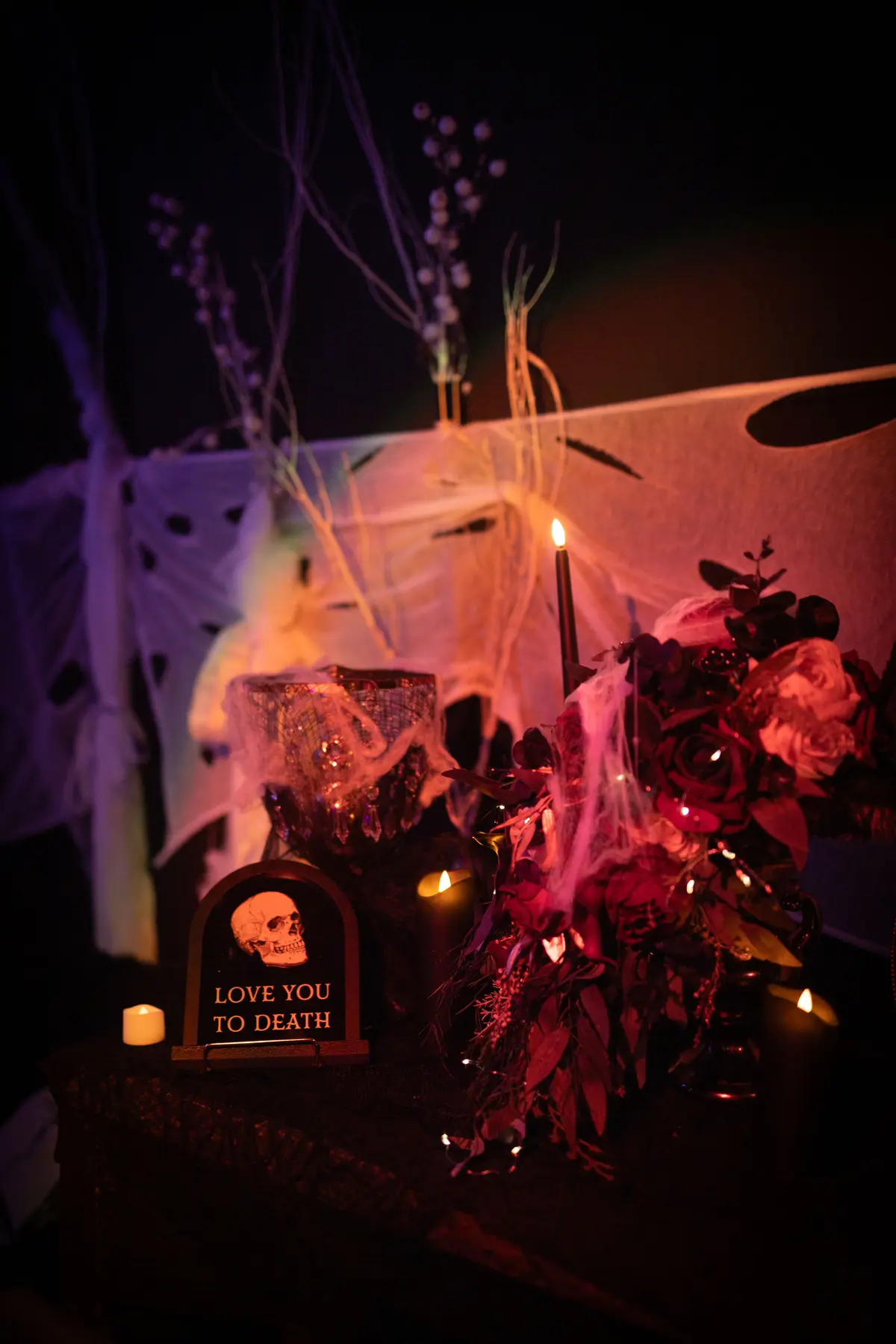 Dark floral installation with candles and a Love You to Death sign