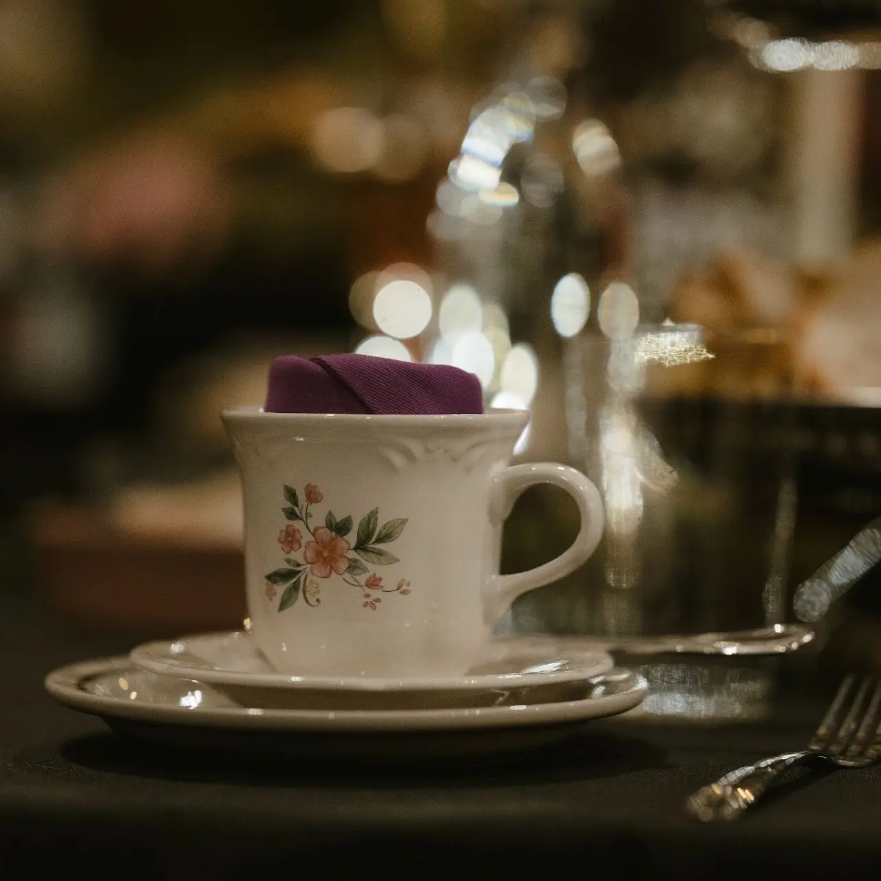 An antique floral teacup set on a candlelit table