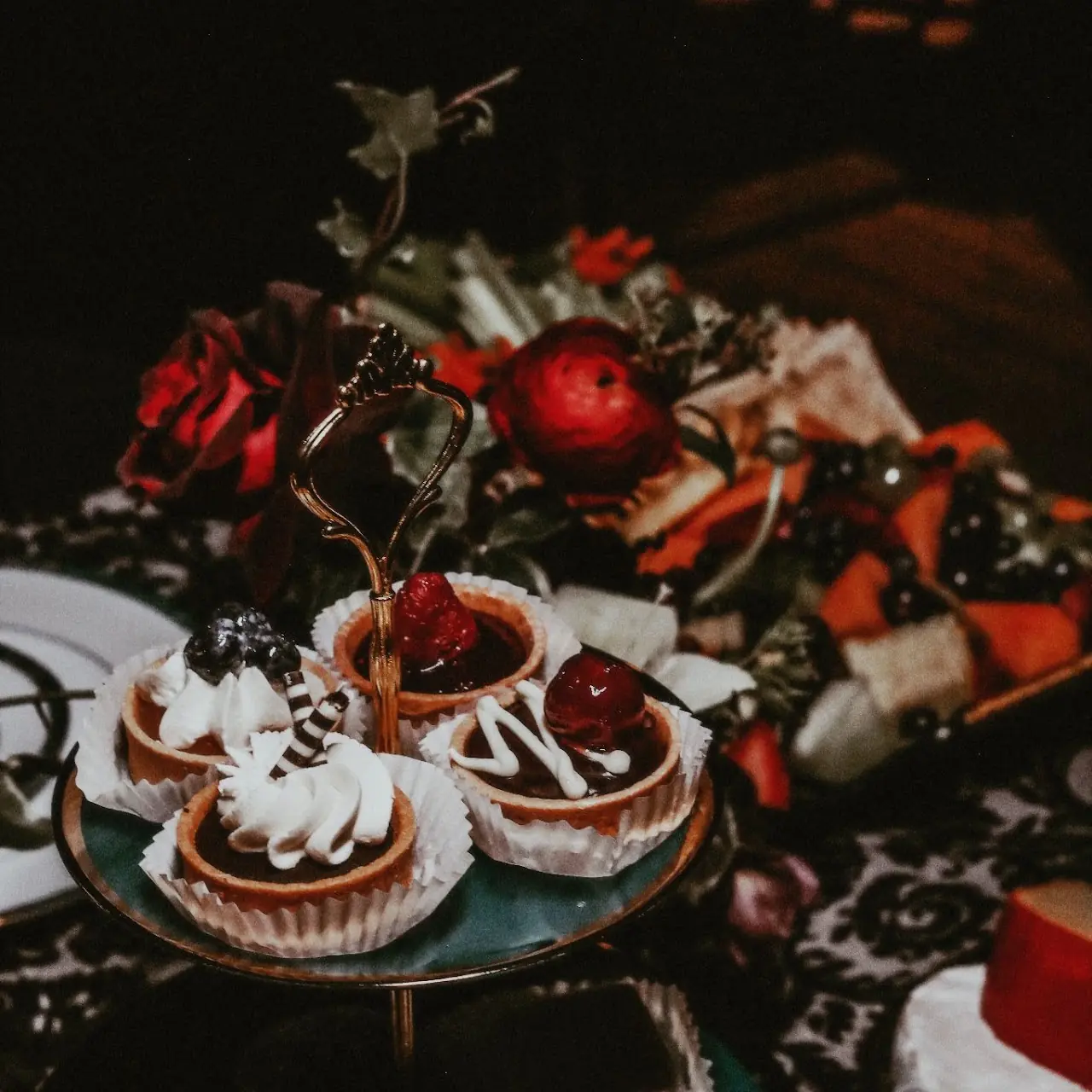 Red and black desserts arranged among dark florals
